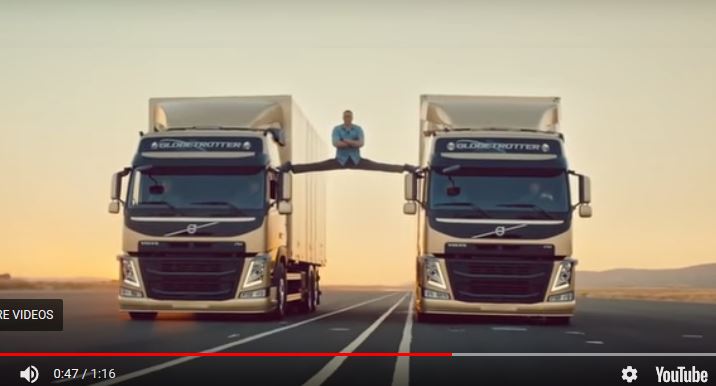 two volvo trucks driving with a man between them